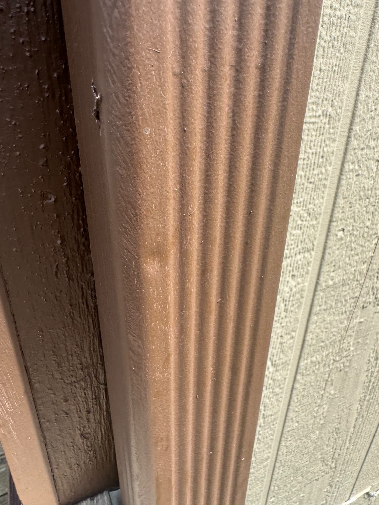 Hail dents documented on a downspout and metal trim during an exterior inspection