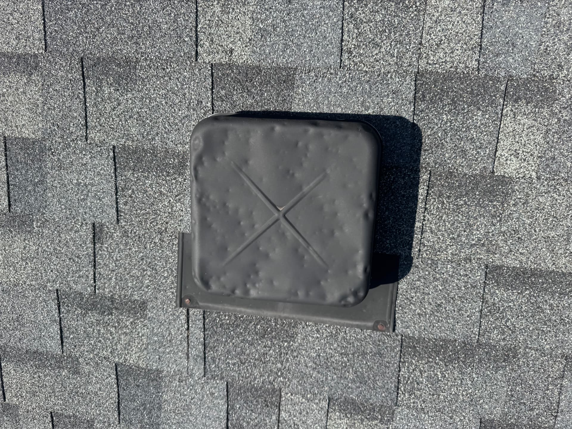 Hail dents across a metal roof vent cap confirming storm impact