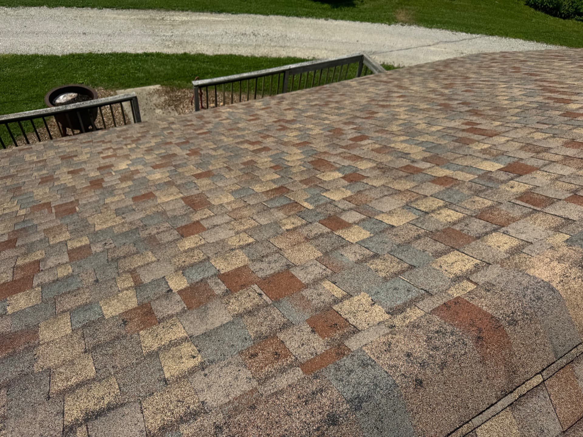 Weathered shingle roof showing granule loss and mismatched repair patches