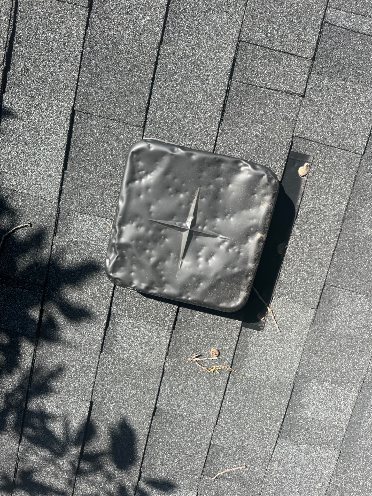 Damaged roof vent with visible hail bruising on a shingle roof